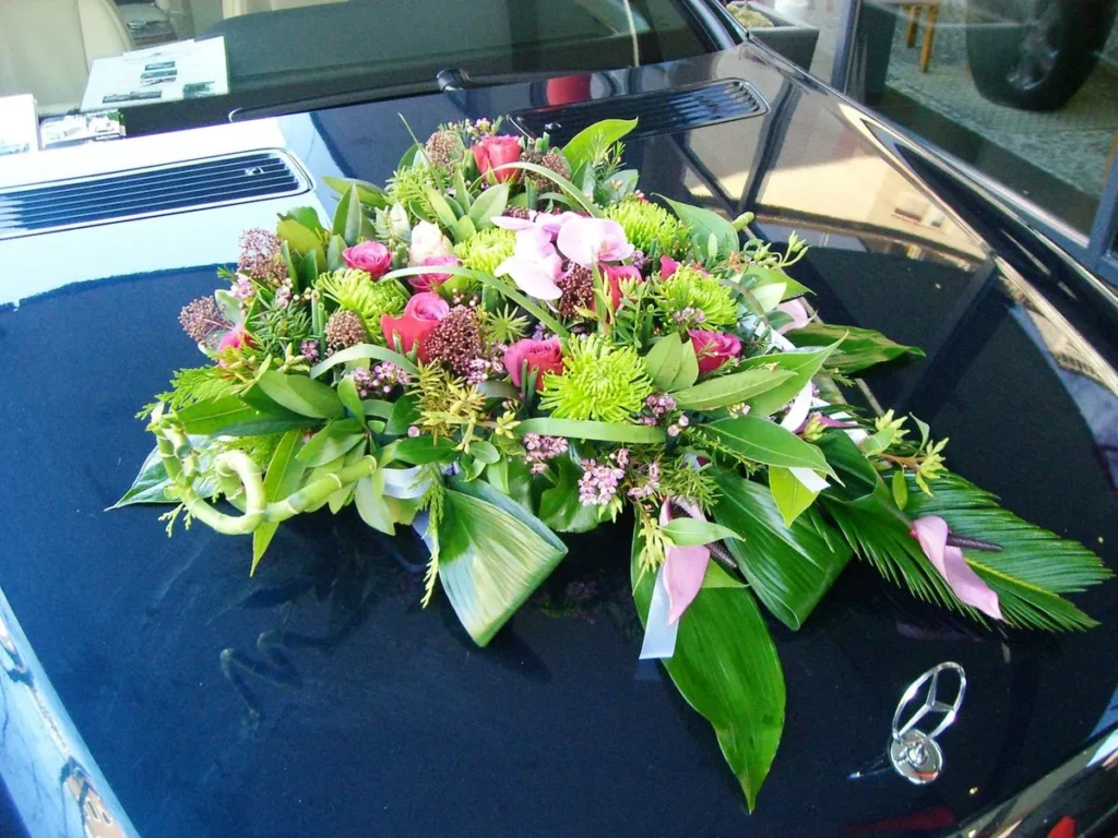 Blumengesteck als Hochzeitsschmuck auf der Motorhaube einer Mercedes-Limousine