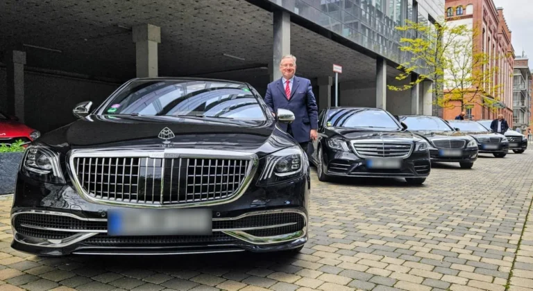 Chauffeur im Anzug neben dem Mercedes-Maybach, dahinter eine Reihe Mercedes S-Klassen