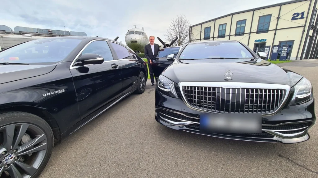 Chauffeur von stars & driver öffnet die Fondtür des Mercedes-Maybach