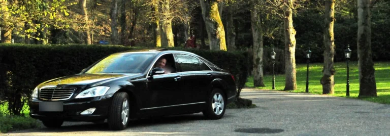 Schwarze Mercedes S-Klasse mit Chauffeur in einem Schlosspark