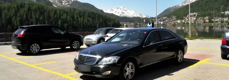 Schwarze Mercedes S-Klasse auf einem Parkplatz in St. Moritz, dahinter See und Berge